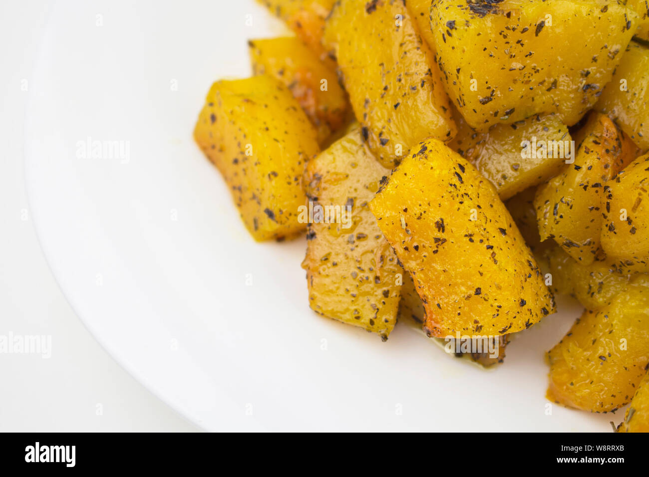 Scheiben von gebackenen Kürbis auf einem weißen Teller. Reife Honig Kürbis in Würfel geschnittenen Kürbis im Ofen gebacken. Bio Gemüse, Ernährung Vegetarische vegane Kost Stockfoto