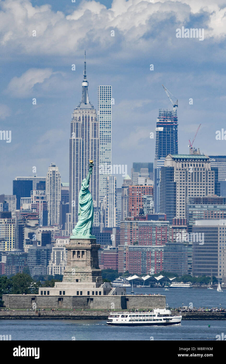 Freiheitsstatue & Skyline von New York City Manhattan im Hintergrund - Freiheit, Symbol der Ellis Island - Empire State Building im Sommer Haze Stockfoto