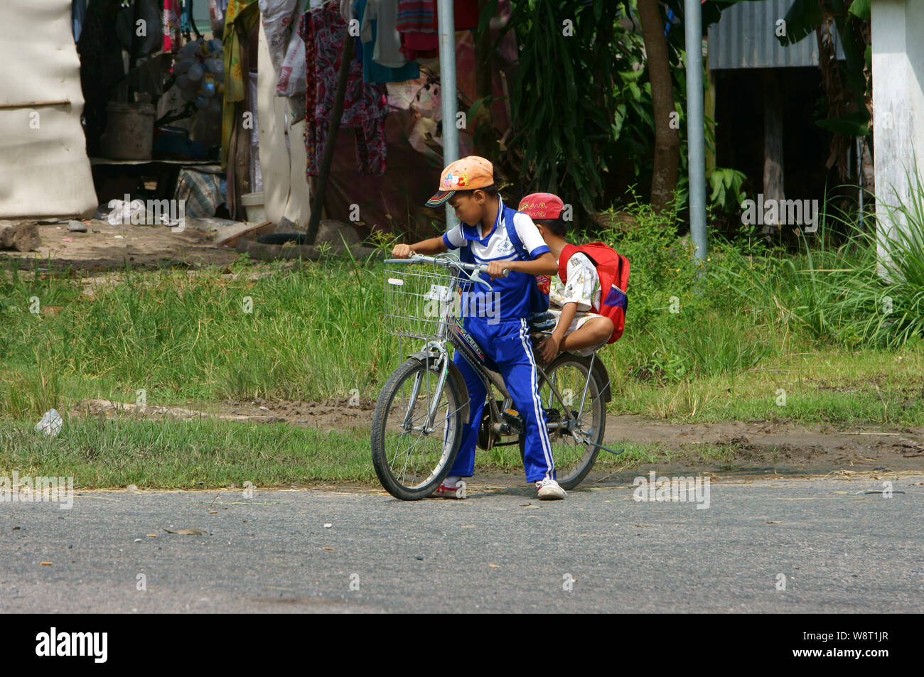 Zwei Vietnamesen kleiner Junge Reiten Fahrrad zur Schule gehen um 12.00 Uhr, Schüler in Uniform Reiten Fahrrad- und Halt am Straßenrand der Autobahn, Vietnam Stockfoto