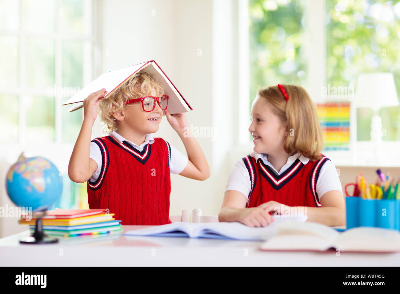 Kinder gehen wieder zur Schule. Kinder Studieren und Lernen für Vorschulkinder. Jungen und Mädchen der Grundschule klasse Hausaufgaben machen. Schlafzimmer mit Schreibtisch, Bücher und Globus fo Stockfoto