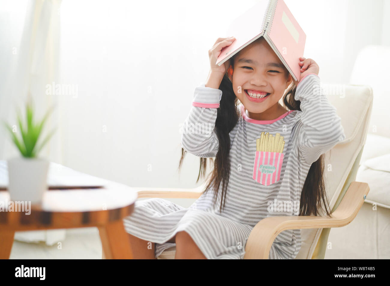 Happy kleines Schulmädchen mit Buch auf dem Kopf. Zurück zum Konzept der Schule. Stockfoto