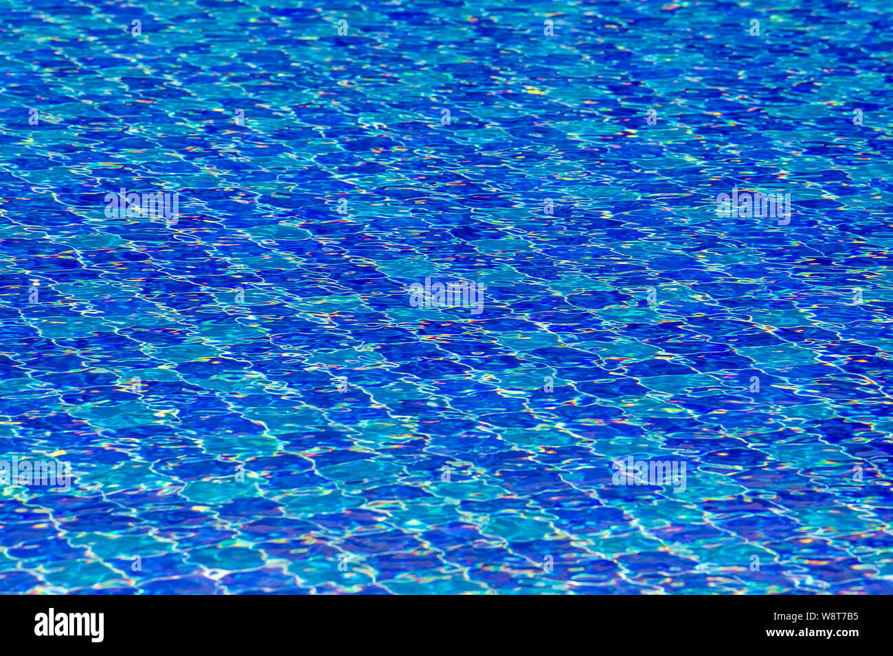 Wasser Wellen auf blau gefliesten Pool Hintergrund. Blick von oben. Blick auf den Pool vor dem Hotel. Wunderschöner Pool Bereit zum Urlaub Touristen. Stockfoto