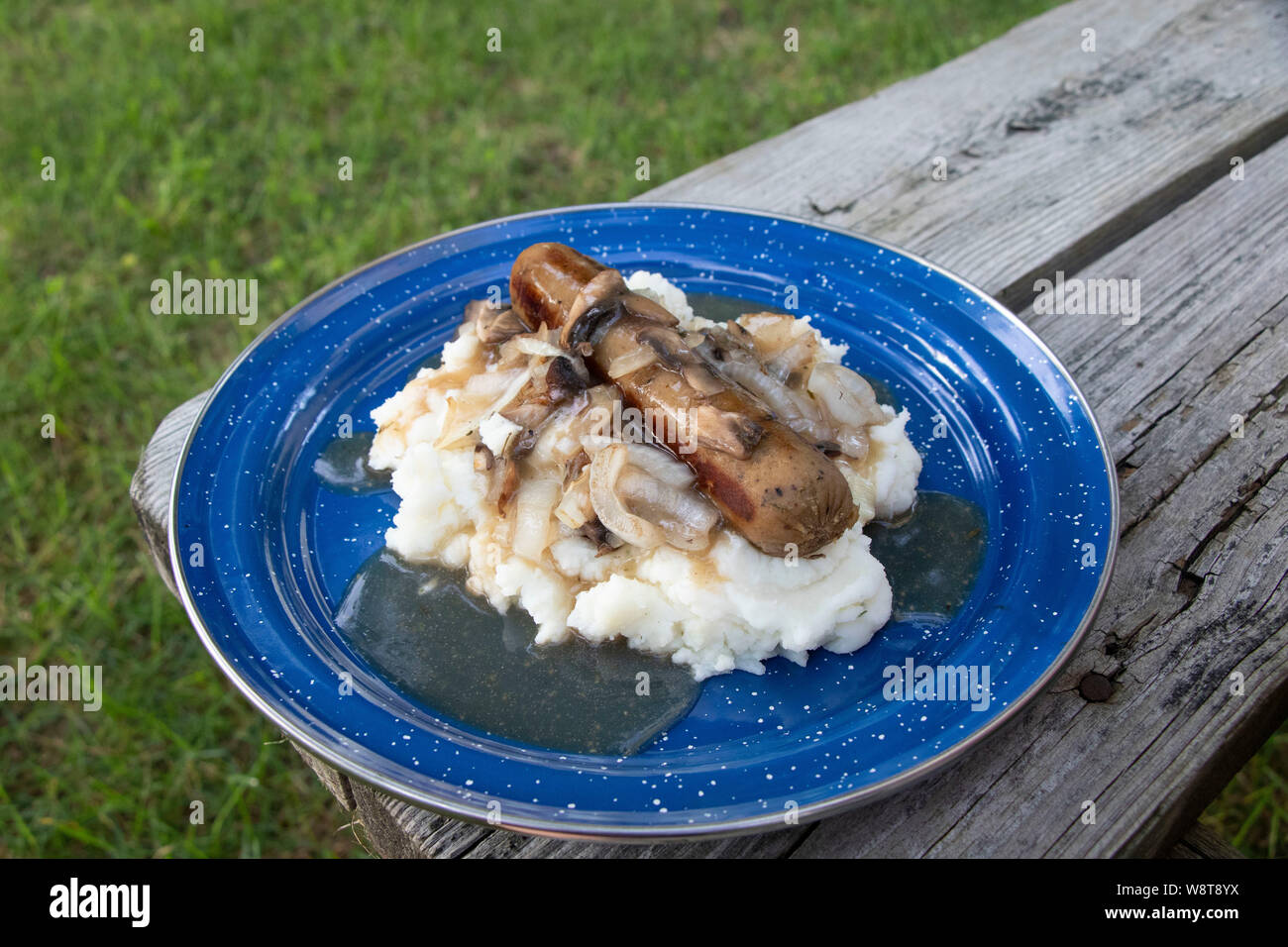 Würstchen mit Kartoffelbrei Close-up mit Champignons in Camping, vegetarisch, vegan, Holz- Picknick Tisch Stockfoto