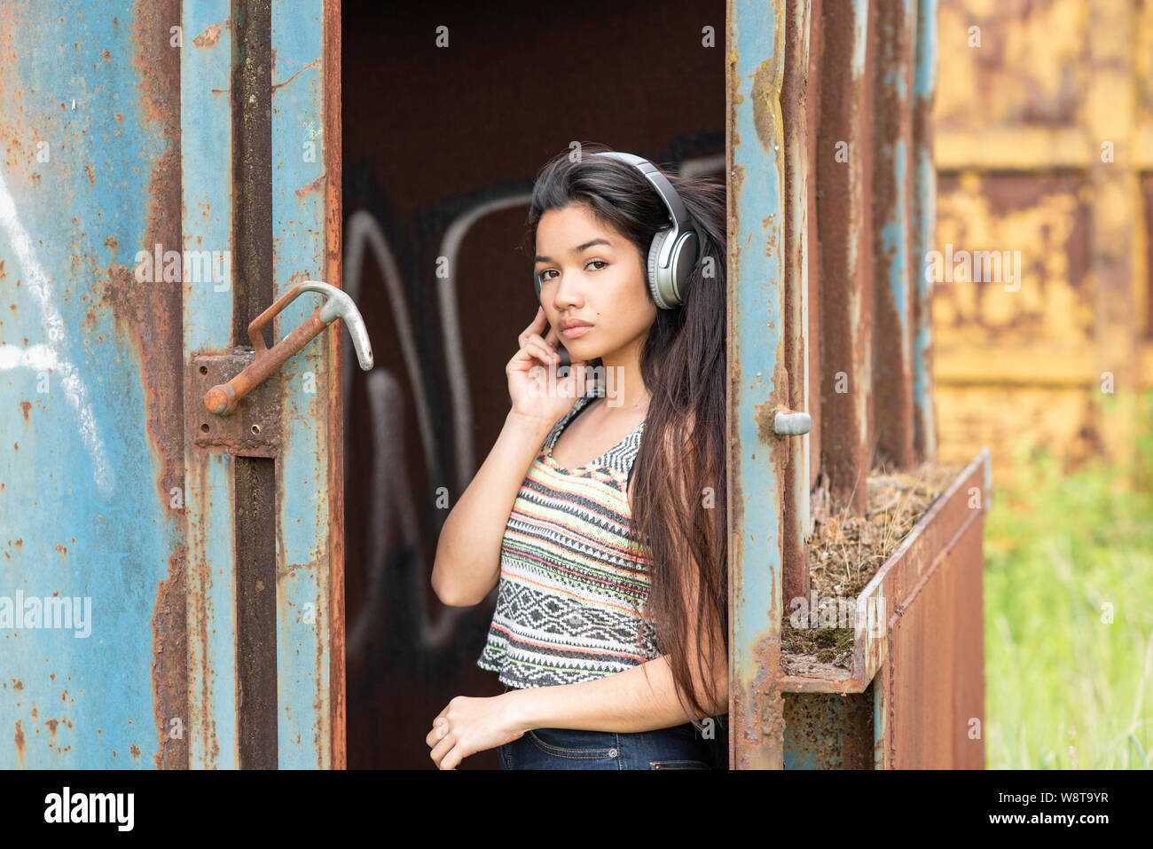 Junge schöne asiatische Frau mit Kopfhörern im Freien Stockfoto