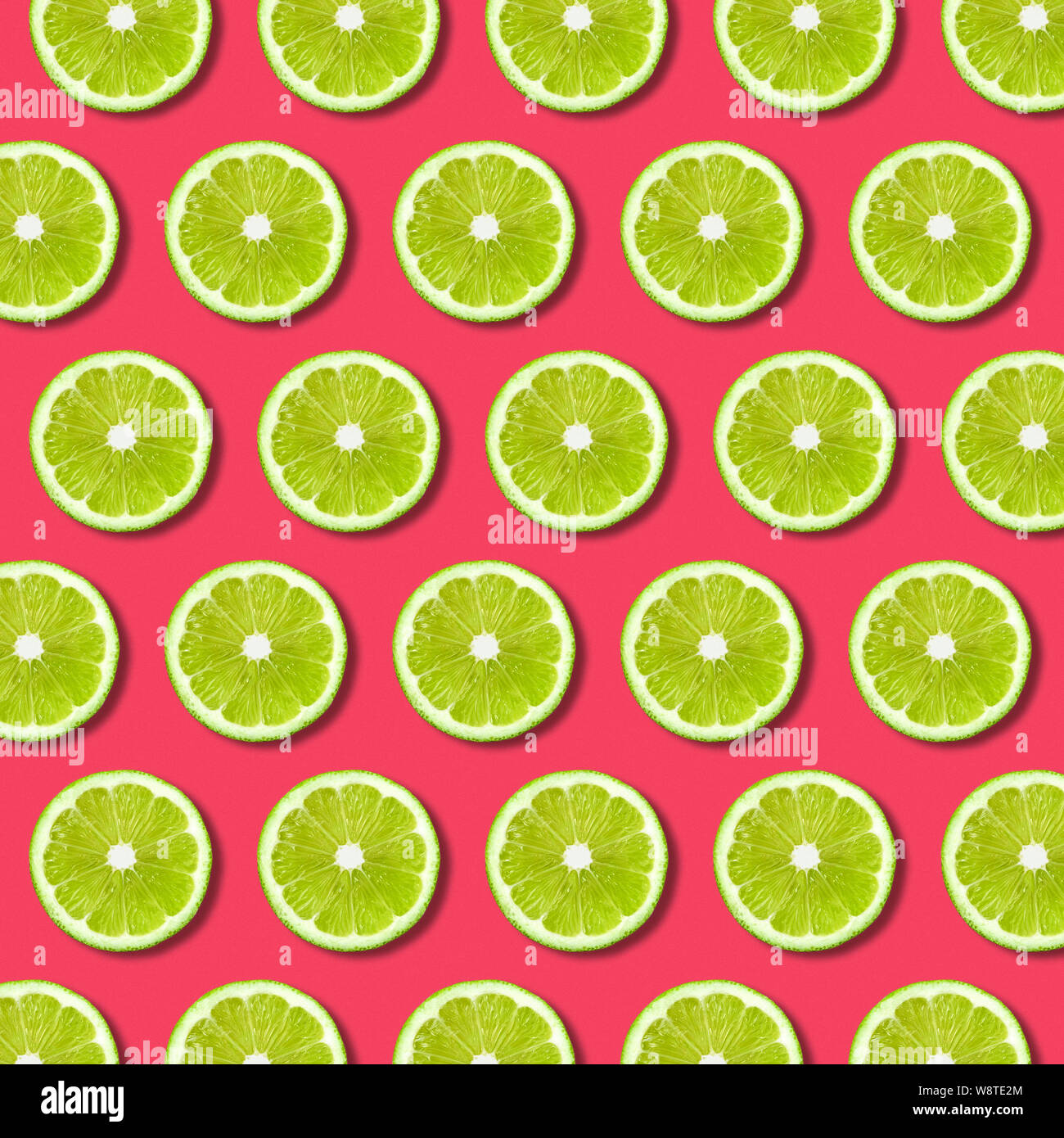 Lebendige Frucht pop art Hintergrund mit grünen Kalk Schichten auf rotem Hintergrund. Minimale flach Essen Muster und Strukturen Stockfoto