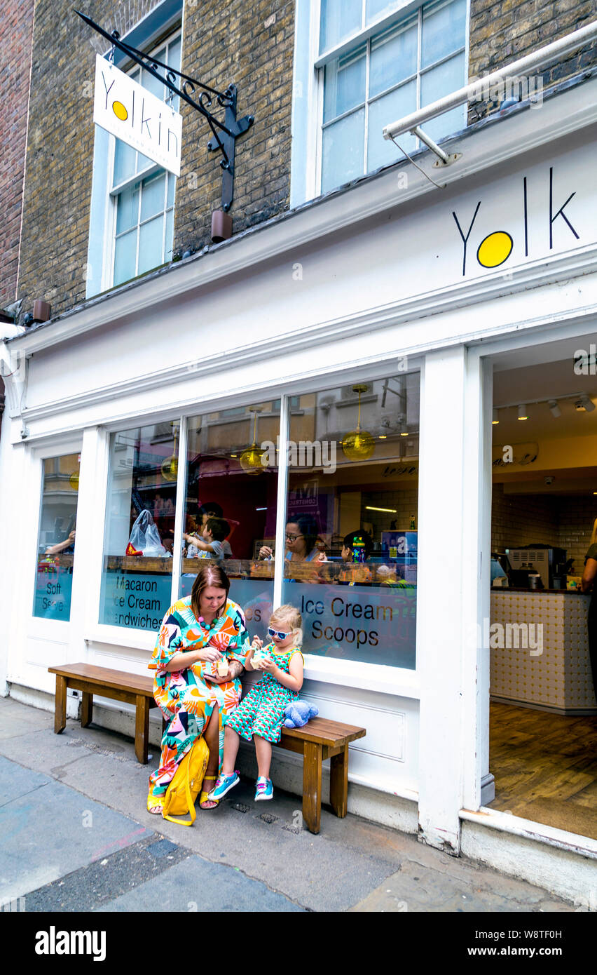 Frau und Kind sitzen vor der Yolkin-Eisdiele, London, Großbritannien Stockfoto