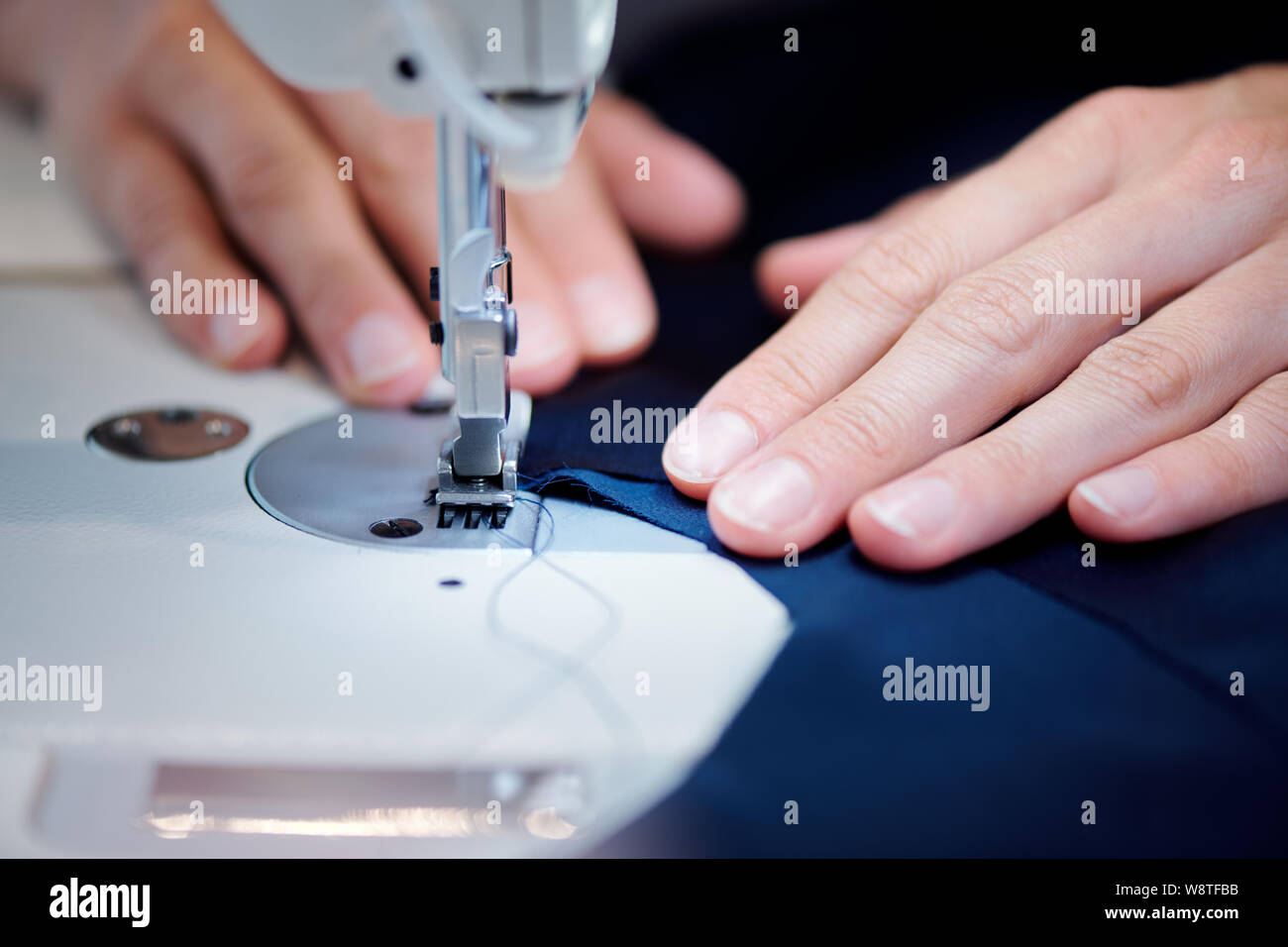 Hände von professionelle Schneiderin holding Stück Stoff in der Nähe Nähnadel Stockfoto