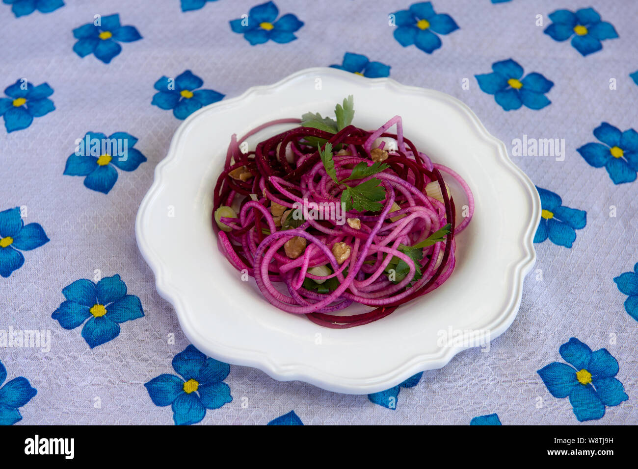 Gesunde imitation Nudeln mit spiralized Rüben, mit Koriander Blätter und Muttern eingerichtet, auf weiße Platte, auf der mit weißen Tischtüchern dekoriert mit Blu Stockfoto