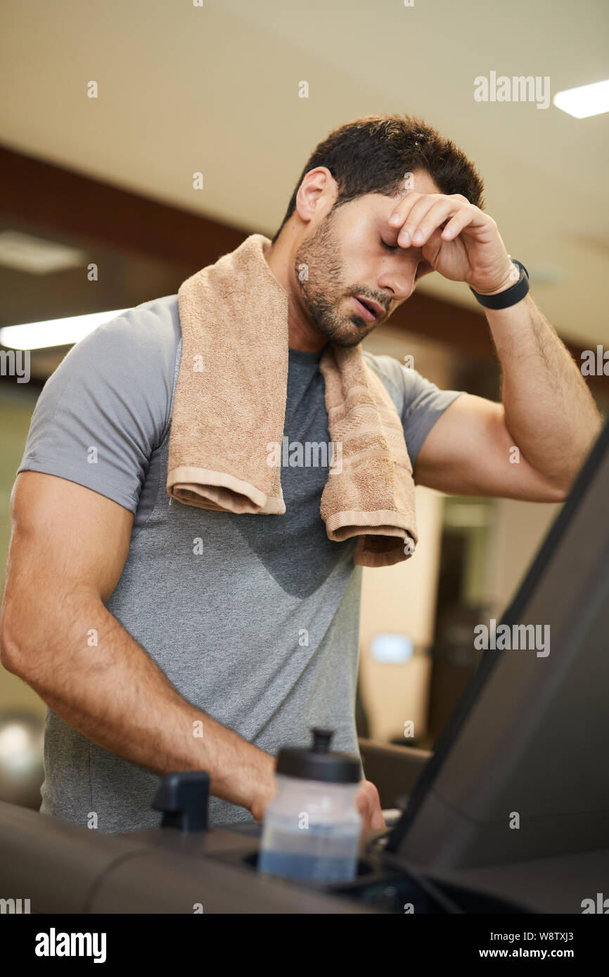 Taille bis Portrait von stattlicher Mann wischen Schweiß während der Ausführung auf Laufband im Fitnessstudio, kopieren Raum Stockfoto