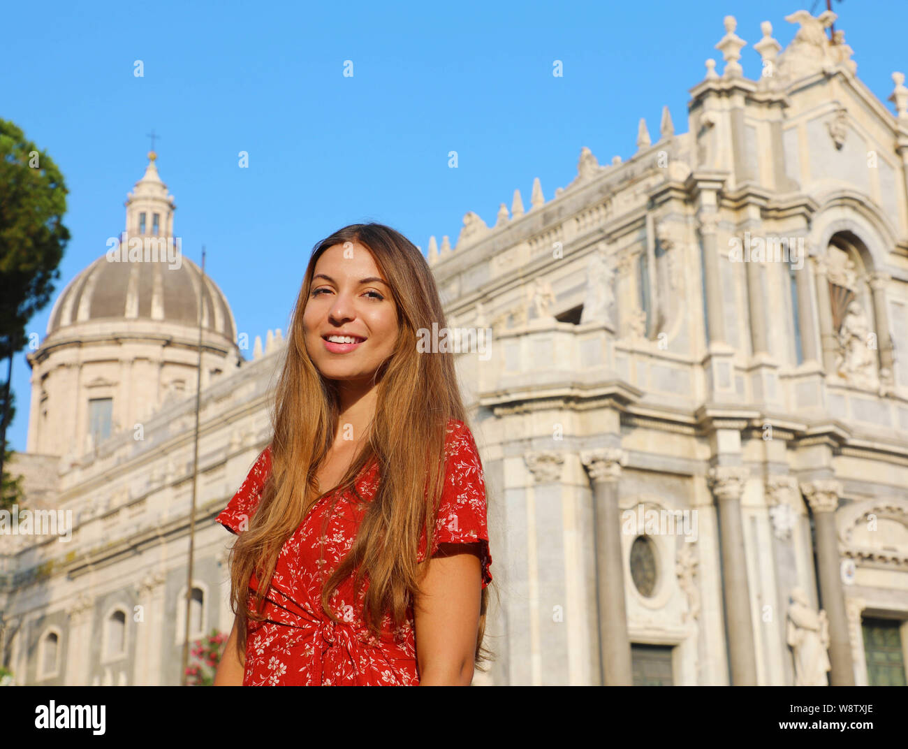 Schönen lächeln Modell vor der Kathedrale von Catania das Tragen der roten Kleid und Kamera. In Sizilien, Italien. Stockfoto