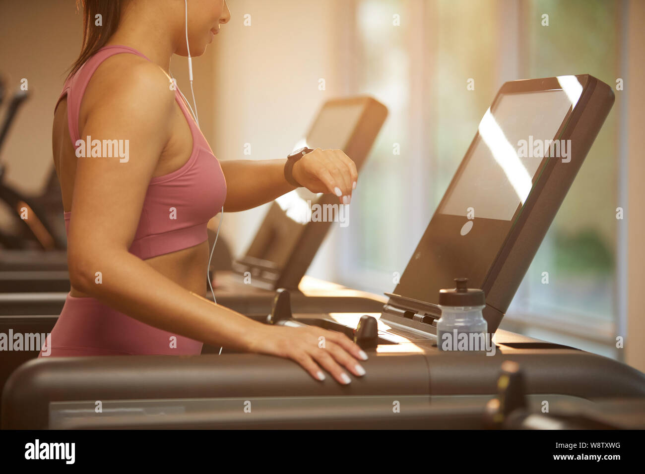 Den mittleren Abschnitt Porträt der schönen jungen Frau, die auf Laufband im Fitnessstudio und Kontrolle smartwatch während cardio Workout, Kopie Raum Stockfoto
