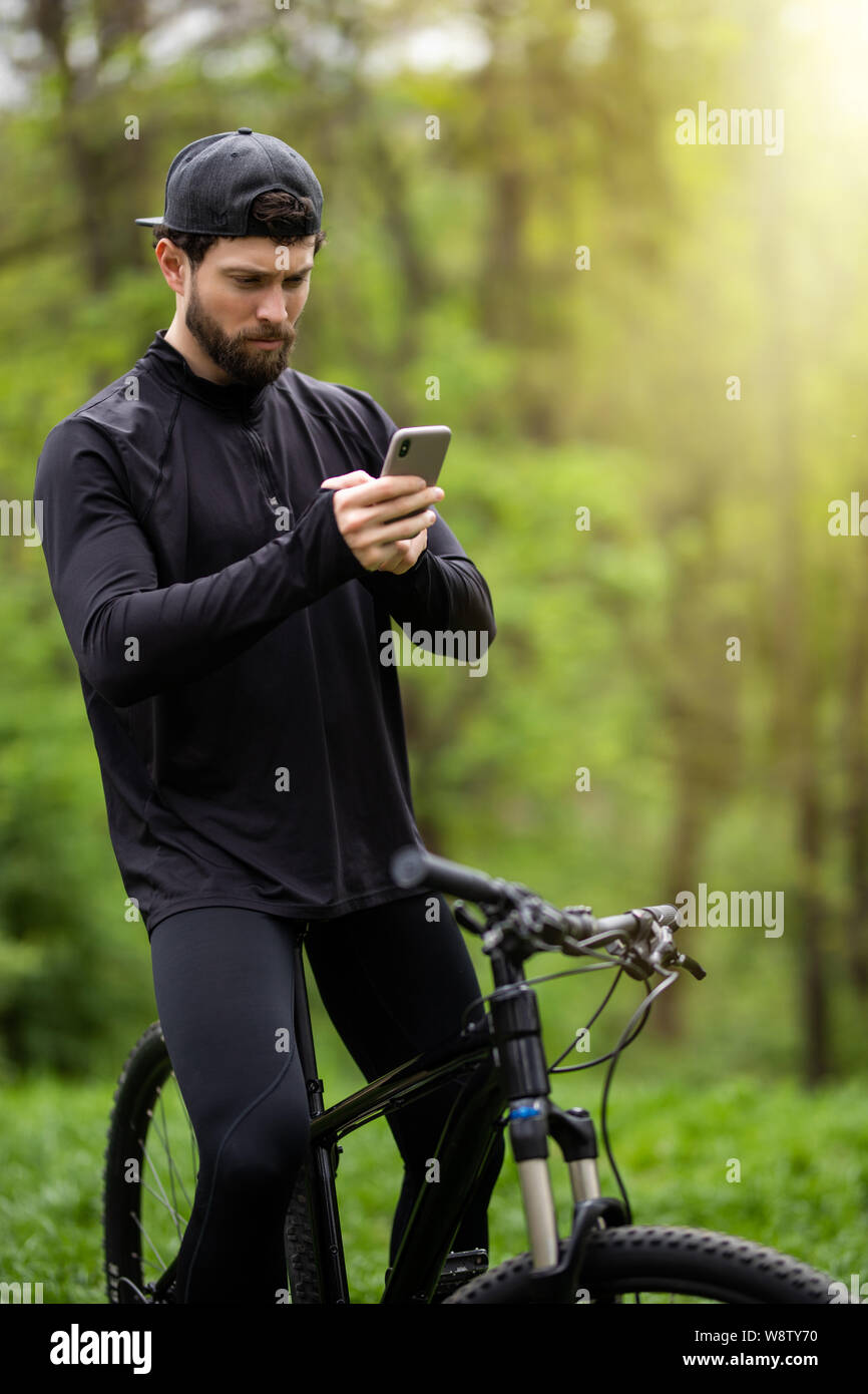 Happy bärtiger Mann Radfahrer Fahrten im sonnigen Wald auf einem Mountainbike. Stockfoto