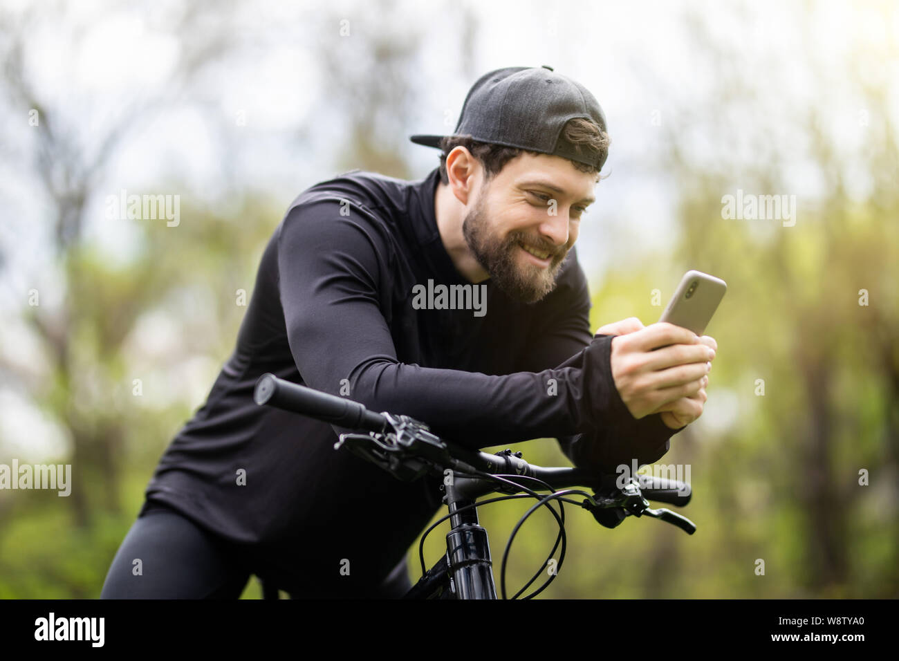 Happy bärtiger Mann Radfahrer Fahrten im sonnigen Wald auf einem Mountainbike. Stockfoto