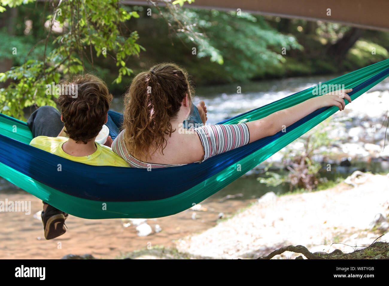 Ein Teenager Paar entspannt in der Hängematte, während Sie auf der Suche an einem Fluss in Meeks Park am 9. Juni 2018 in Blairsville, Ga. Stockfoto