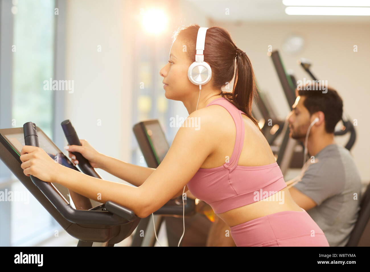 Seitenansicht Porträt der jungen Frau das Tragen von Kopfhörern trainieren im Fitnessraum, Kopie Raum Stockfoto