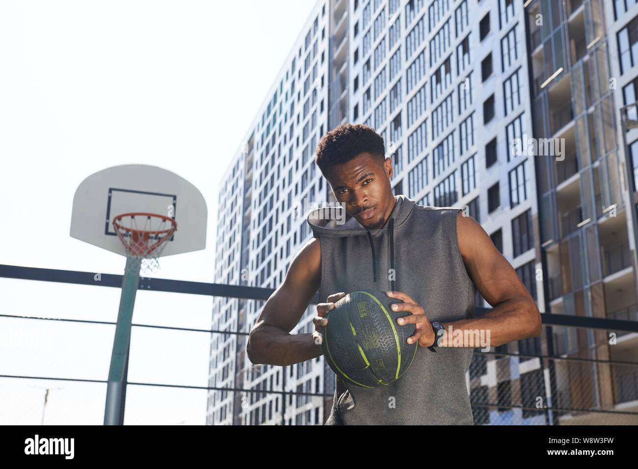 Taille bis Portrait von stattlichen Afrikaner - Mann mit Basketball Ball und bei Camera zuversichtlich beim Stehen in der außenplatz, kopieren Raum Stockfoto