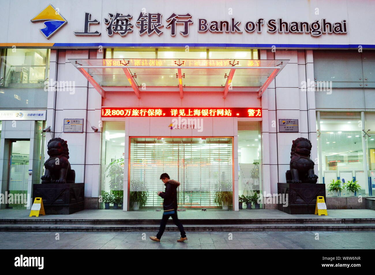 ---- Eine Fußgängerzone nutzt sein Handy, als er an eine Filiale der Bank von Shanghai nach Hangzhou City, East China Zhejiang provinz, 11. Dezember Stockfoto
