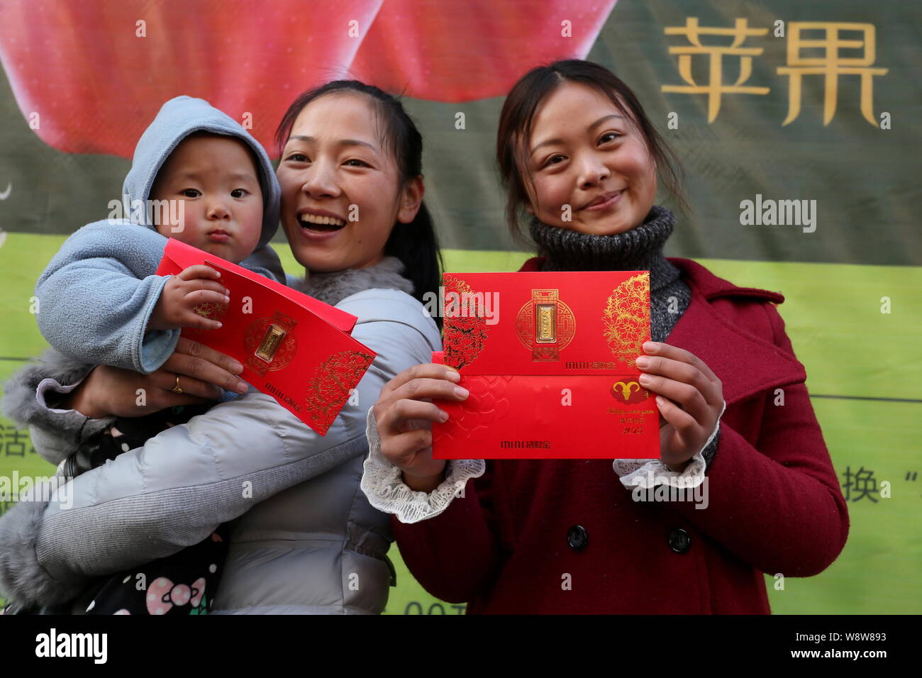 Kunden zeigen die kleinen Stücke aus Gold, die sie für Äpfel vor einem Juweliergeschäft in Zhengzhou city ausgetauscht, Chinas Provinz Henan, 23 De Stockfoto