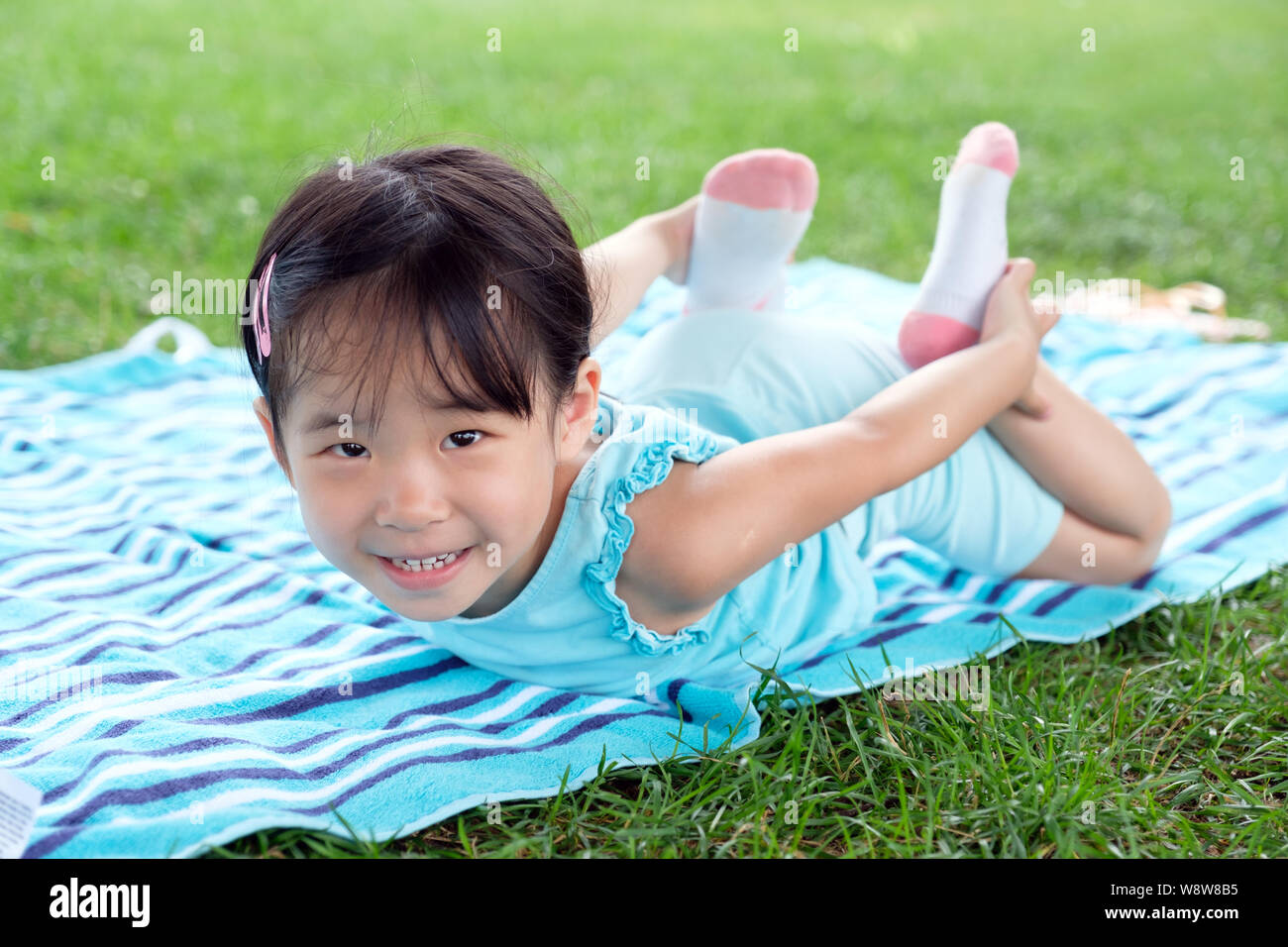 Wenig kleinkind Mädchen mit auf dem Handtuch im Gras im Sommer Stockfoto