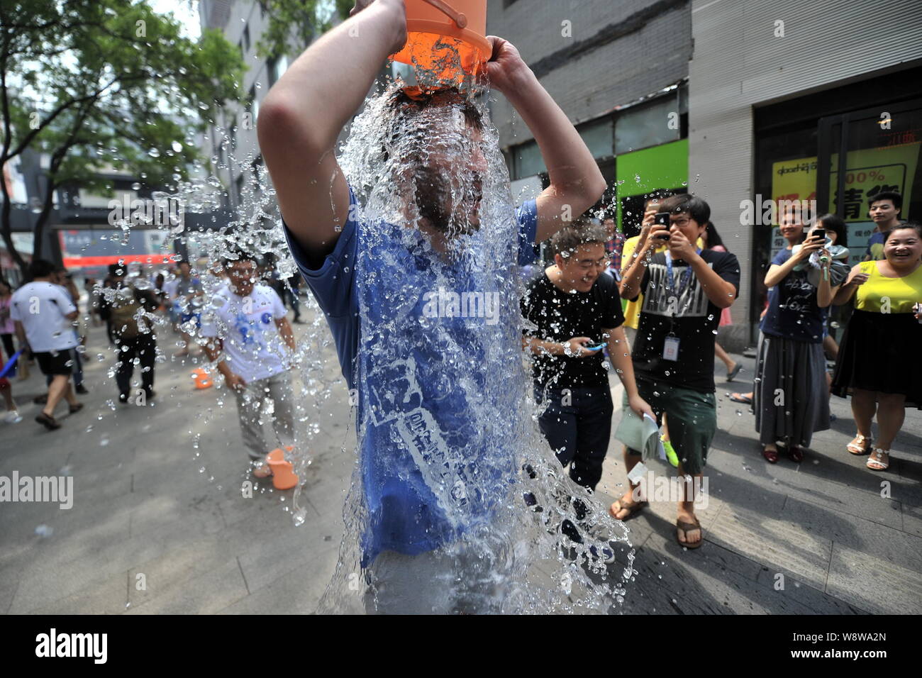 Junge Leute richten entlang einer Straße den Eimer für das Eis Herausforderung in Zhongguancun, tapfer, auch als China's Silicon Valley, in Peking, China, 21. August bekannt Stockfoto