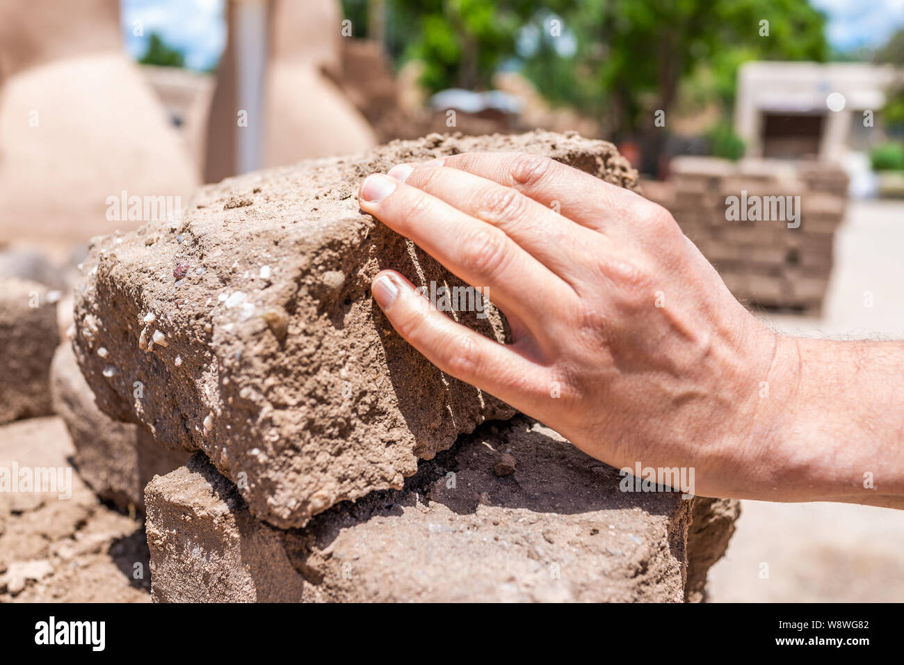 Nahaufnahme der Hand berühren Adobe Schlamm Sonne getrocknete Backstein Übersicht detail und Textur, während der Bauarbeiten in Neu Mexiko Stockfoto