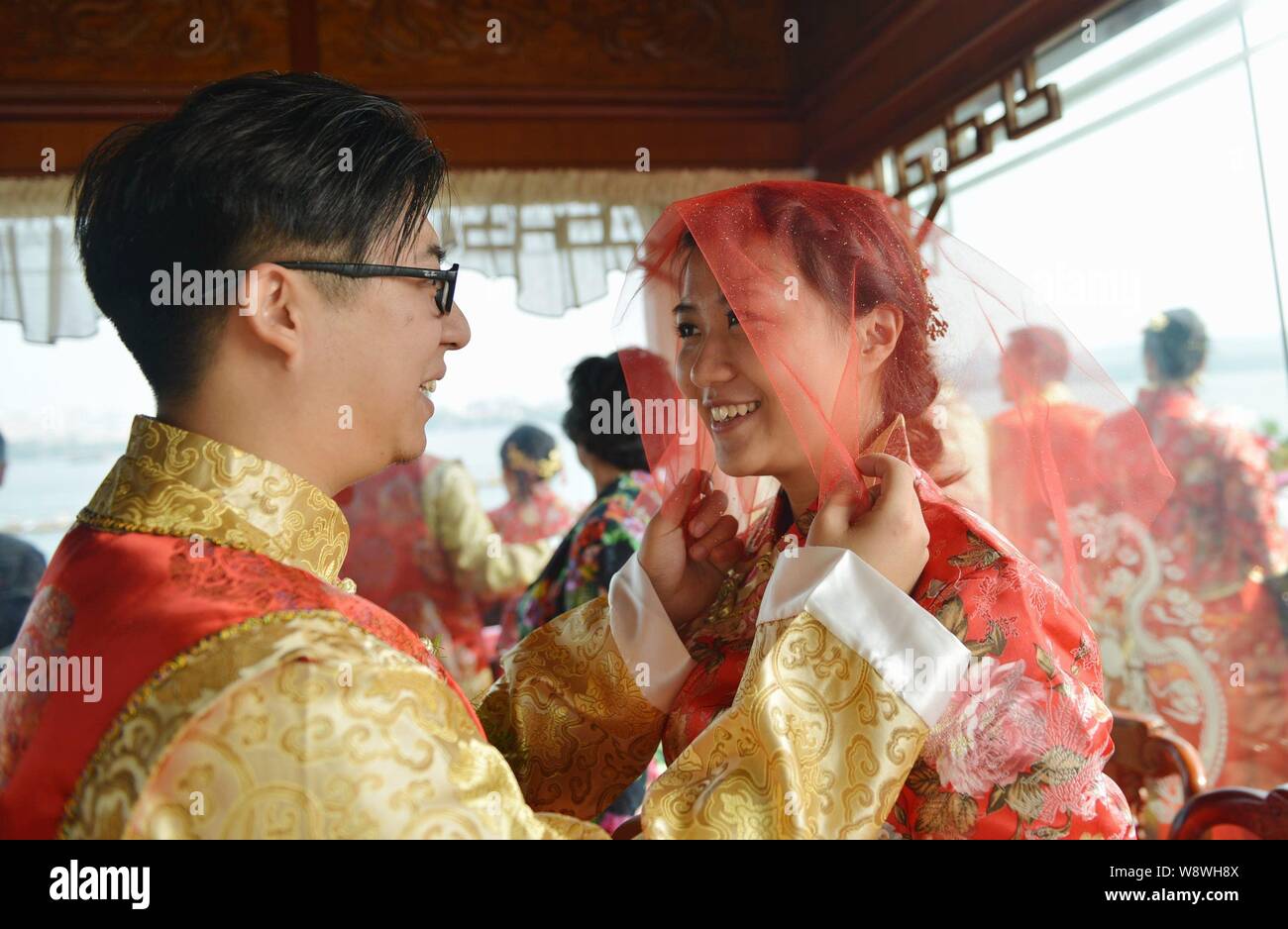 Paare Brautpaare, die in traditionellen chinesischen Kostümen Teil in einem kollektiven Trauung in einem Boot auf dem Westsee in Hangzhou City, Stockfoto