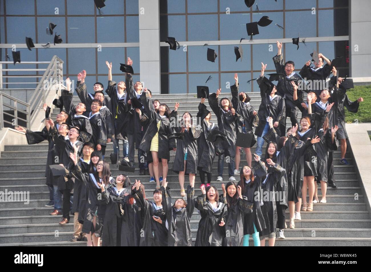 ------ Chinesische Absolventen der akademischen Gewänder gekleidet werfen Hüte in die Luft eine Graduierung eine Fotografie an der bezirksfreien Stadt Liaocheng zu feiern. Stockfoto