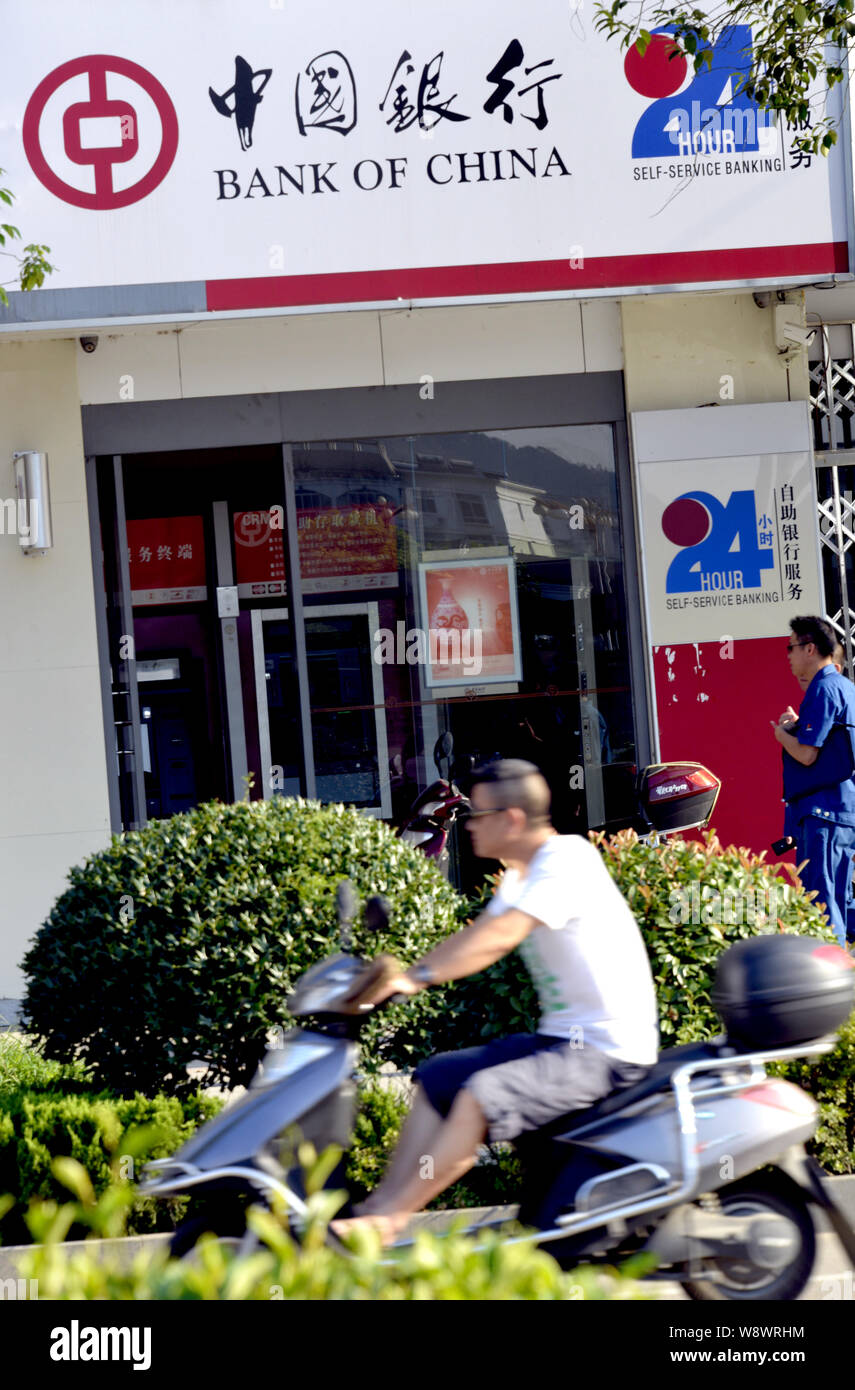 ---- Ein Mann fährt mit dem Elektrofahrrad Vergangenheit eine Filiale der Bank of China (BOC) in Dexing City, East China Provinz Jiangxi, 23. Juli 2014. Bank von China Stockfoto