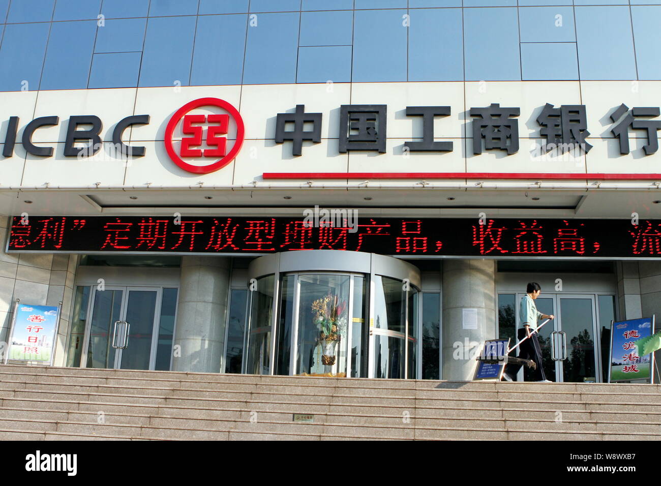 ---- Eine chinesische Reinigung Arbeitnehmer Spaziergänge Vergangenheit ein Zweig der ICBC (Industrielle und kommerzielle Bank von China) in Rizhao, East China Provinz Shandong Stockfoto