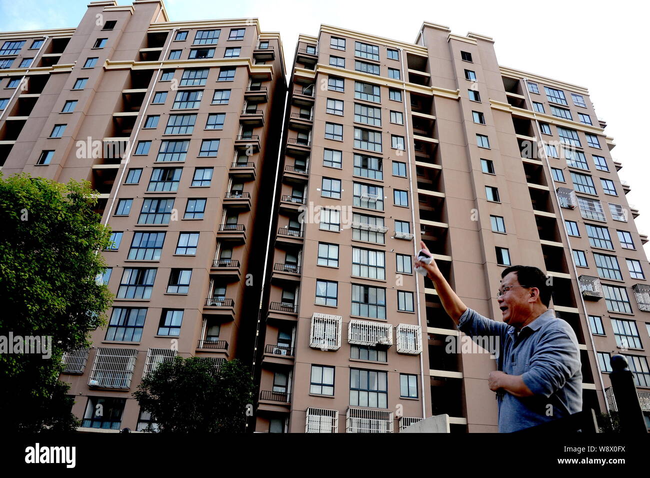 Einen lokalen chinesischen Bewohner spricht mit anderen vor dem zwei Wohnhäuser, stoßen einander auf der Traufe am Xinyuan West Gemeinschaft Stockfoto