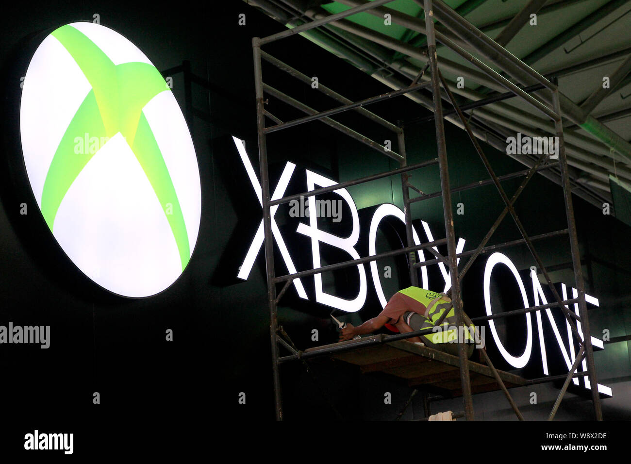 Ein chinesischer Arbeiter installiert ein Aushängeschild einer Xbox, die vor der Eröffnung des 12. China Digital Entertainment Expo, auch als ChinaJoy 2014 bekannt, in Sha Stockfoto
