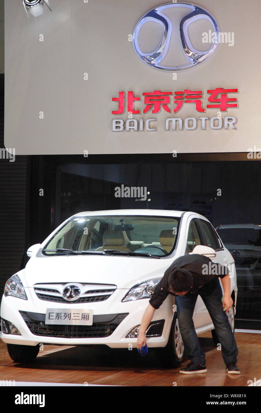---- Ein Angestellter reinigt ein BAIC E-Serie Auto am Stand von baic (Beijing Automotive Industry Holding Co., Ltd.) Während ein Automobil ausstellung Stockfoto