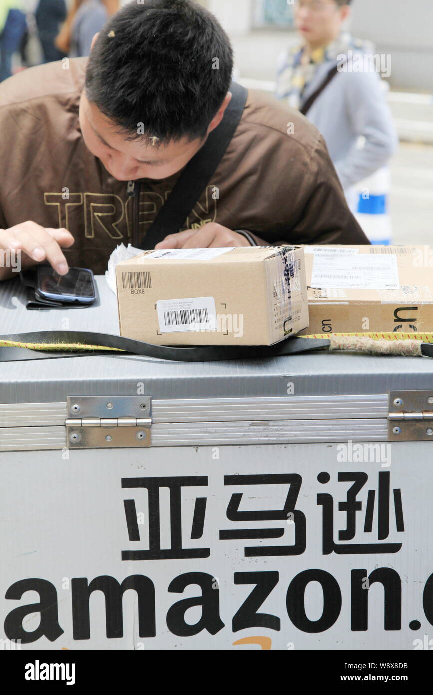 ---- Eine chinesische Kurier des e-commerce Riese Amazon nutzt sein Smartphone einen Kunden zu kontaktieren, wie er liefert Pakete in Nanjing City, East China Jia Stockfoto