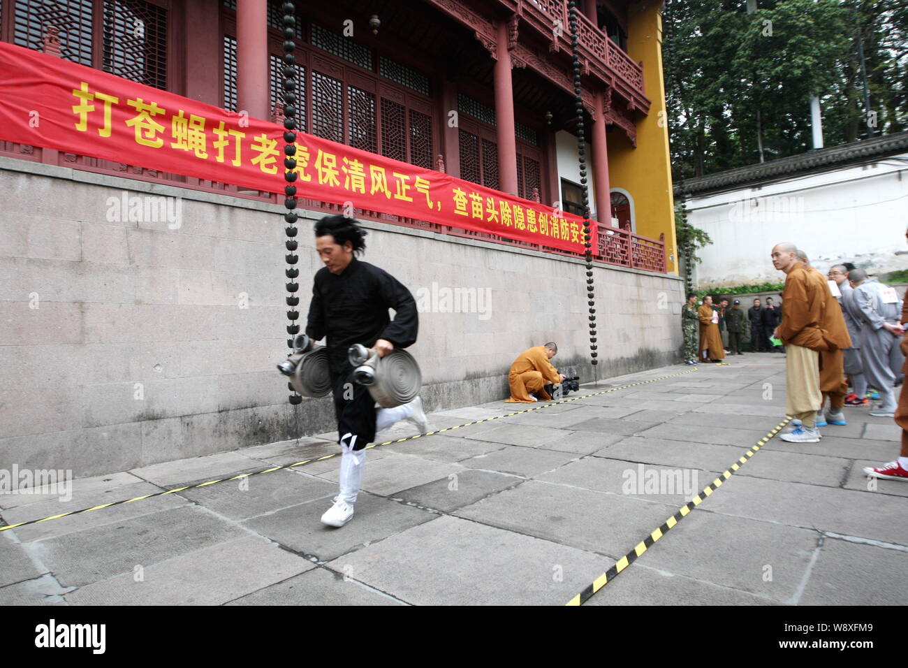 Ein chinesischer Taoistischer Mönch die Wasserschläuche konkurriert in einem Wettlauf bei der Brandbekämpfung Spiele bei Lingying Tempel in Hangzhou City, East China Zheji Stockfoto