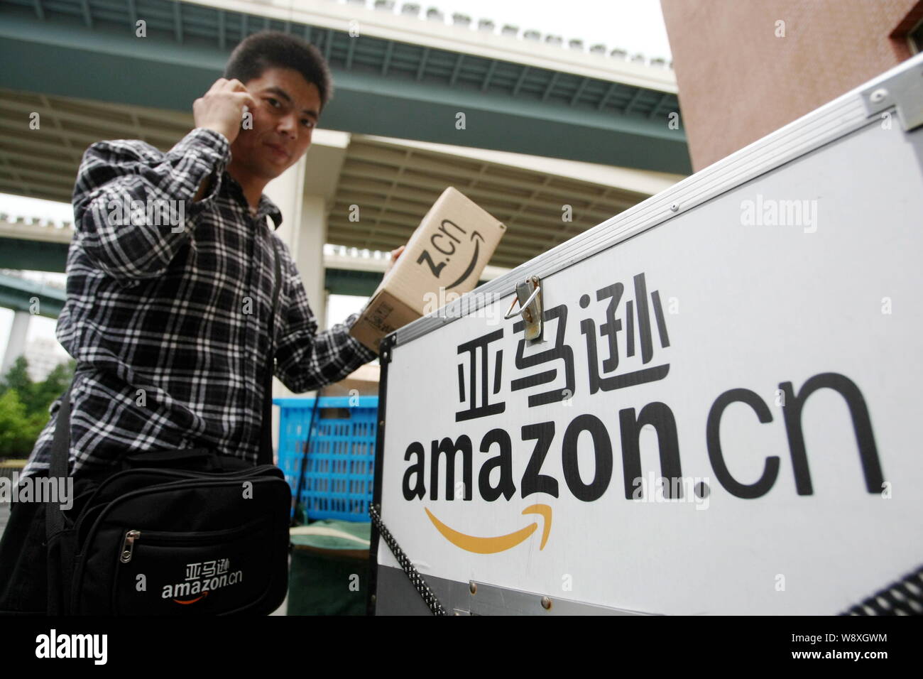 ---- Eine chinesische Kurier des e-commerce Riese Amazon fordert ein Kunde als Er liefert nach Angaben der DPAG in Shanghai, China, 1. Juli 2013. Amazon sagt, es sig hat Stockfoto