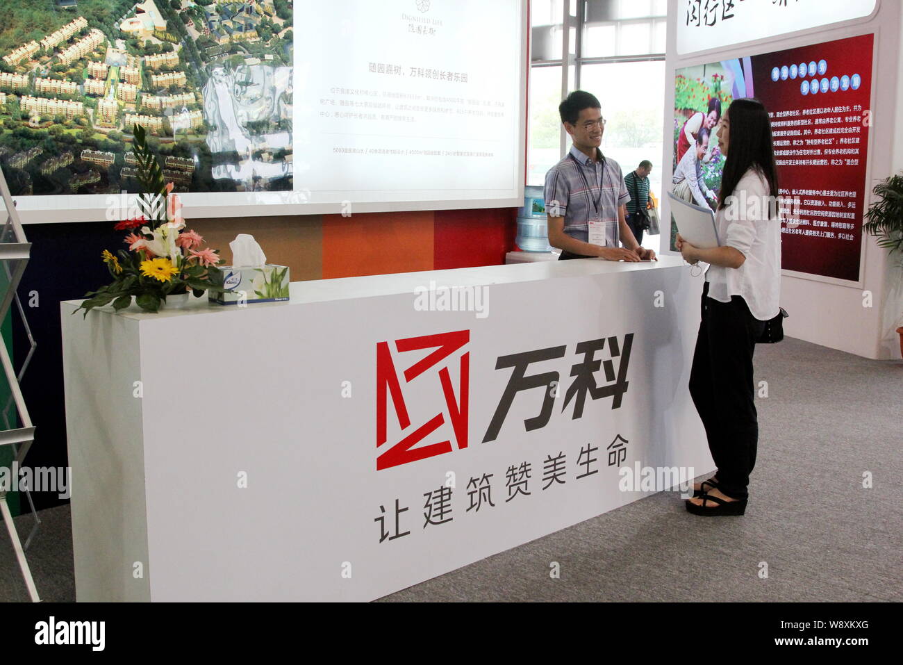 Ein Mitarbeiter spricht mit einem Besucher am Stand von Vanke während einer Ausstellung in Shanghai, China, 26. Mai 2014. China größte Eigenschaft Entwickler sieht Stockfoto
