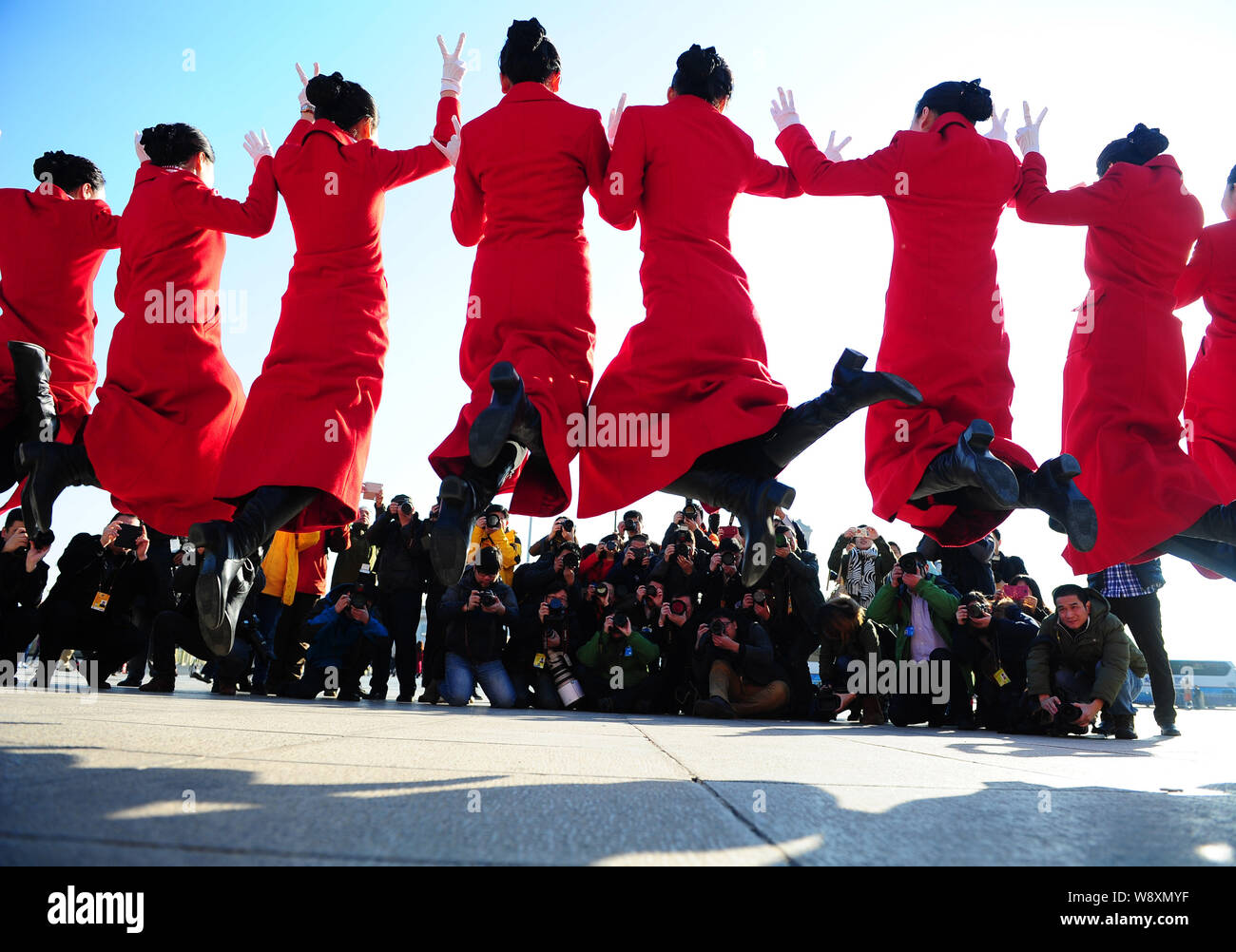Chinesische Hostessen in rote Uniformen springen und posieren für Fotos vor der Eröffnung der zweiten Tagung des 12. NPC (Nationale Leute Stockfoto