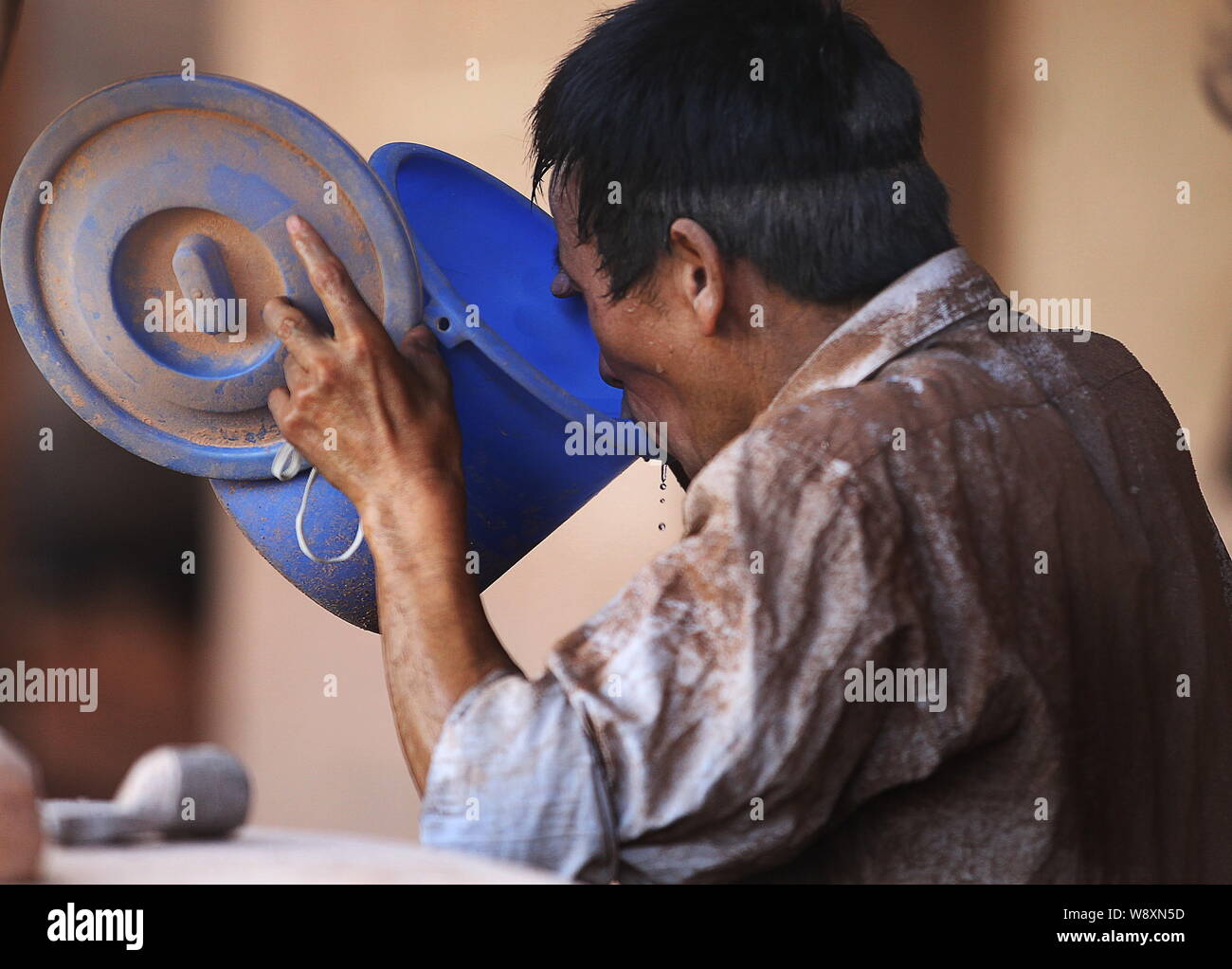 ---- Ein chinesischer Arbeiter mit alunite Staub aller Getränke Wasser an einem alaun Fabrik im Fanshan Stadt, Cangnan County, Wenzhou City, East China abgedeckt Stockfoto