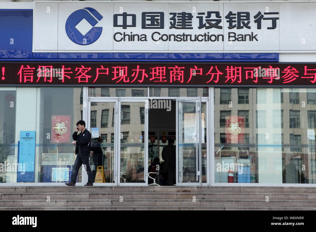 ---- Ein Kunde Gespräche über sein Handy, als er einen Zweig der China Construction Bank (CCB) in Rizhao Stadt verlässt, East China Provinz Shandong, 16. Stockfoto
