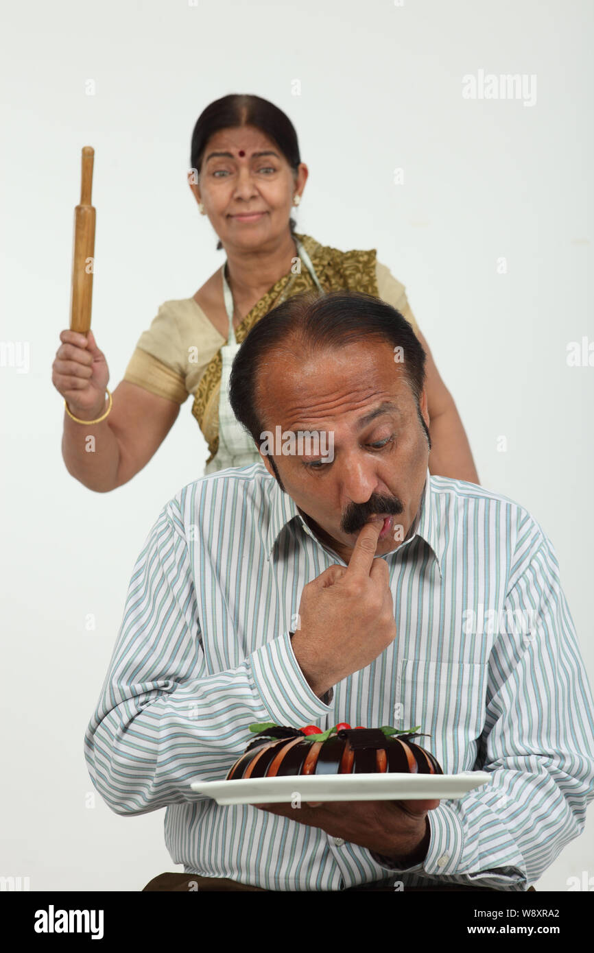 Mann beim Kuchen essen mit seiner Frau im Hintergrund Stockfoto