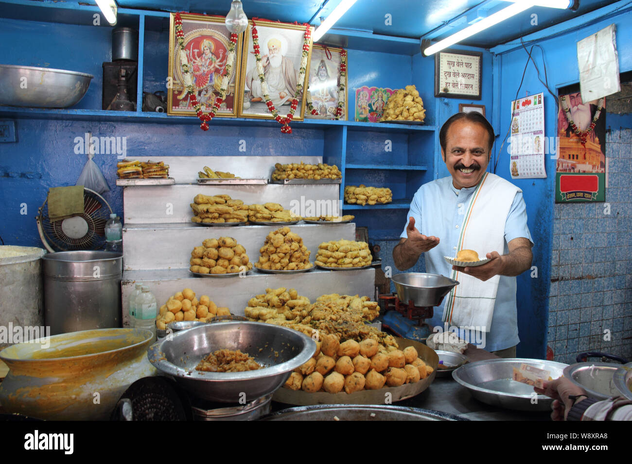 Ladenbesitzer gibt einem Kunden einen Teller Pakora Stockfoto