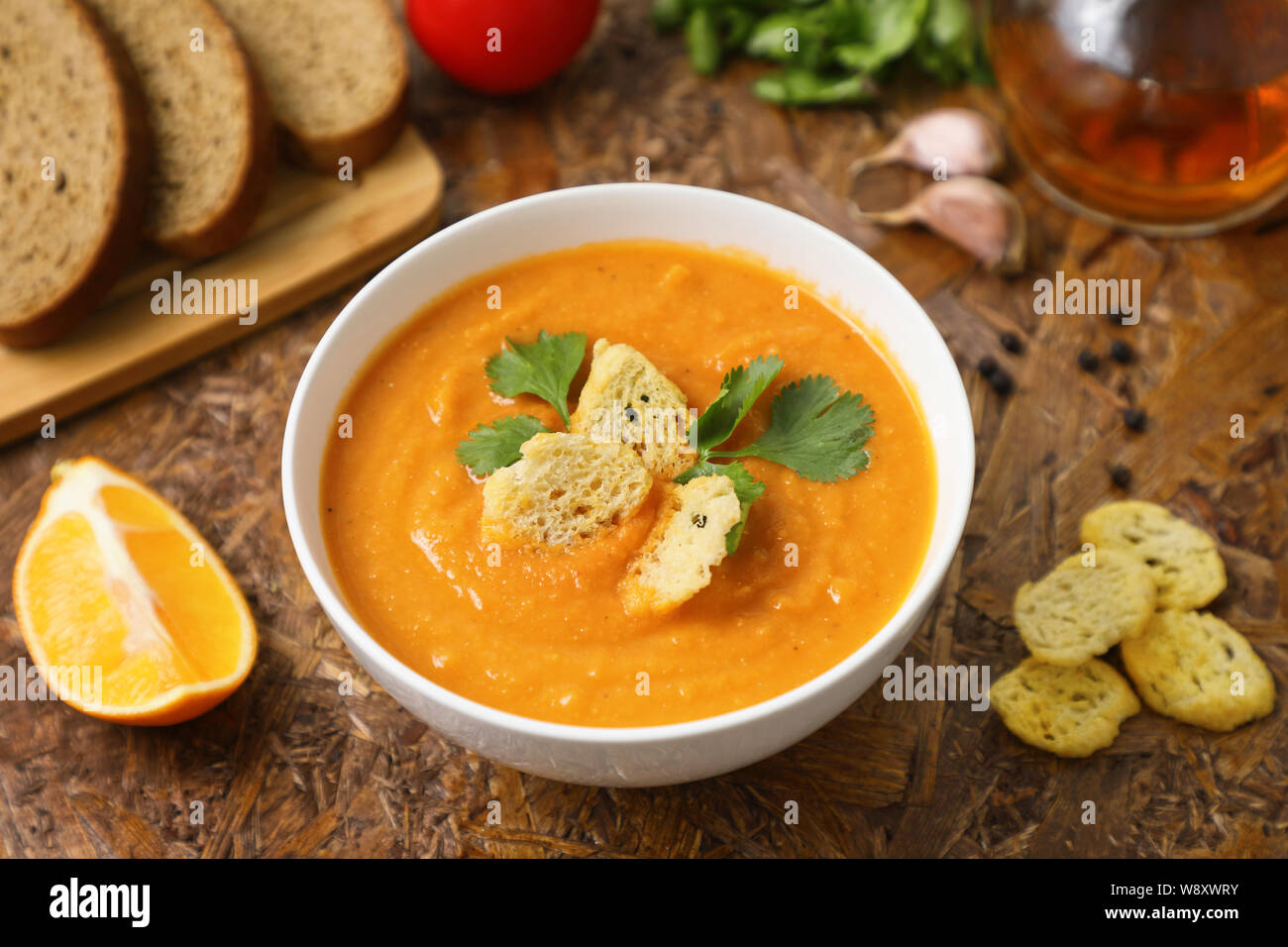 Reich an pflanzlichen Proteinen Linsensuppe pürieren. Toast und Zitrone. Tomaten und grünen. Braun strukturierten Hintergrund. Stockfoto