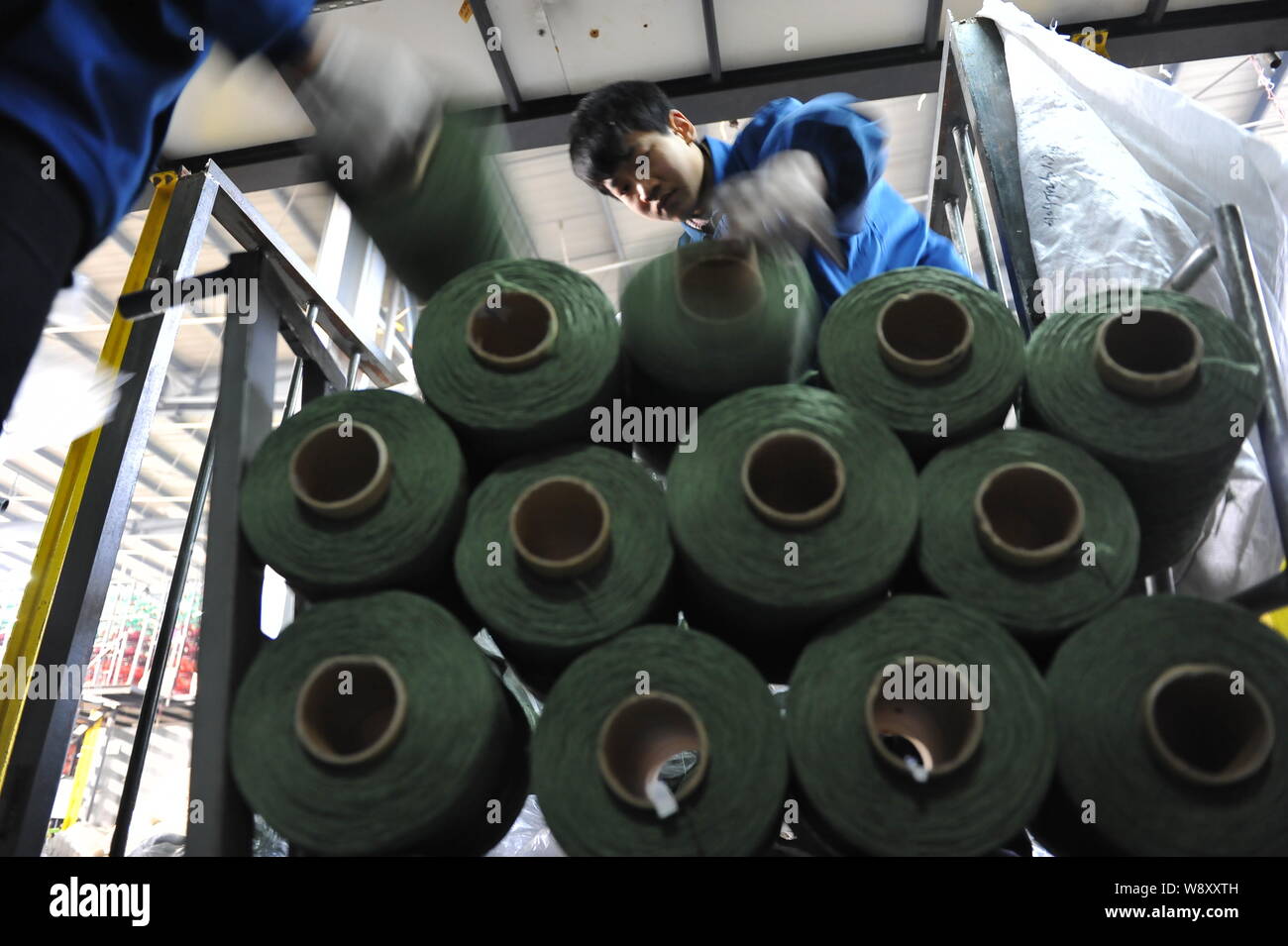 ------ Chinesische Arbeiter stapeln Rollen Garn in einer Teppichfabrik in Rizhao City, East China Provinz Shandong, 20. Februar 2014. Ein Manometer von mainl Stockfoto
