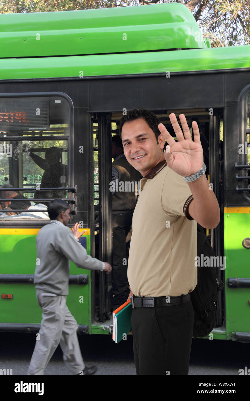 College-Student winkt Hand vor einem DTC-Bus Stockfoto