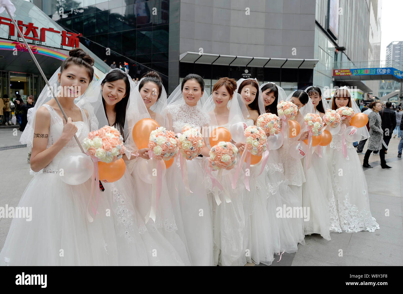 Einzelne Frauen in Hochzeit Kleider gekleidet halten Blumensträuße und Luftballons vor Singles Tag am Wanda Square in Chongqing, China, 9. November 20. Stockfoto