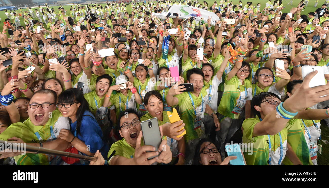 Freiwillige verwenden ihre Smartphones selfies während einer Abschiedsfeier im Nanjing Olympic Sports Center Stadion während der 2014 Sommer Jugend Oly zu nehmen Stockfoto