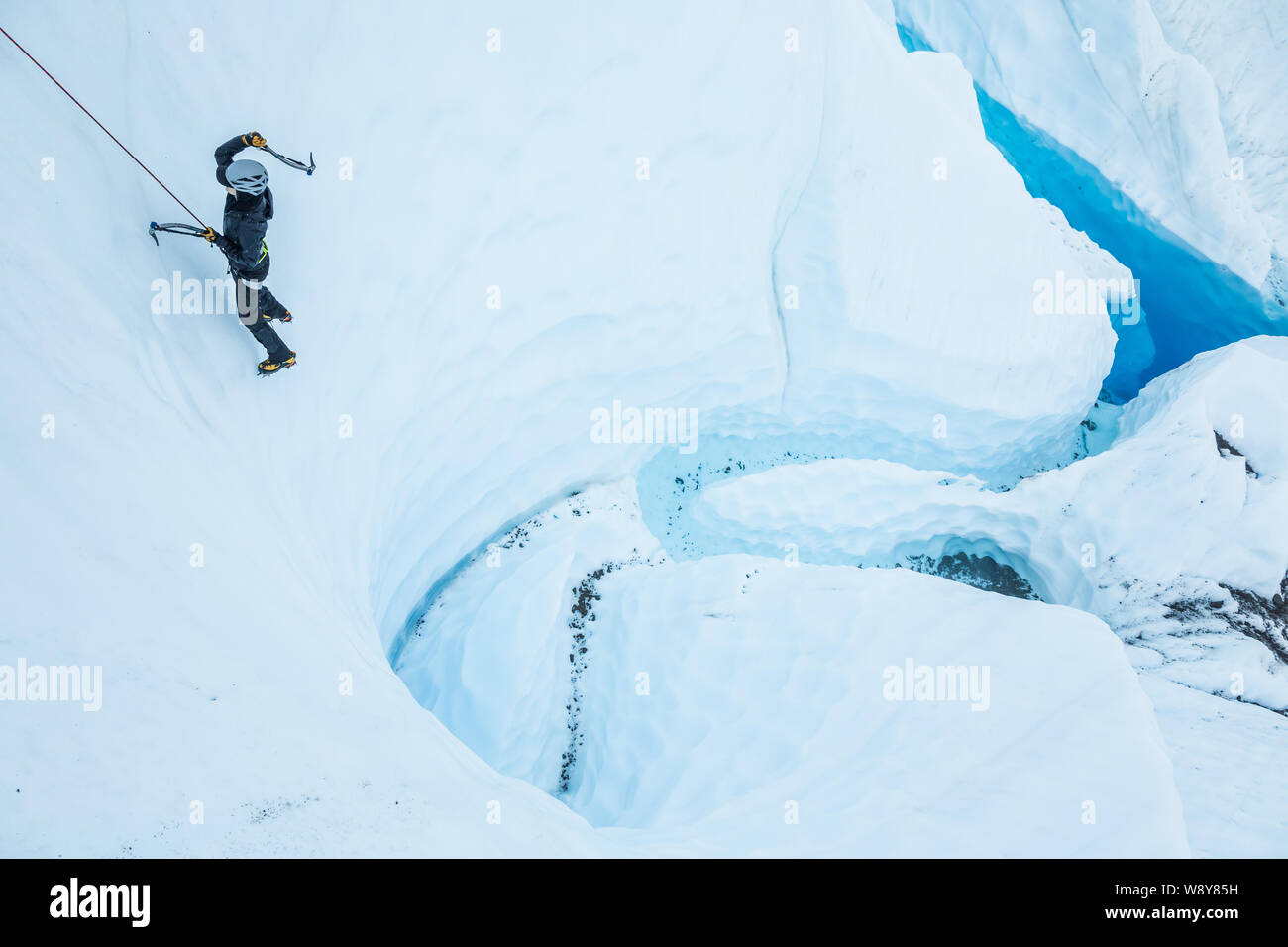 Glacier River und Deep Blue Pool auf der Matanuska Gletscher in Alaska. Eine junge Frau steigt eine vertikale Wand über den schönen blauen Wasser. Stockfoto