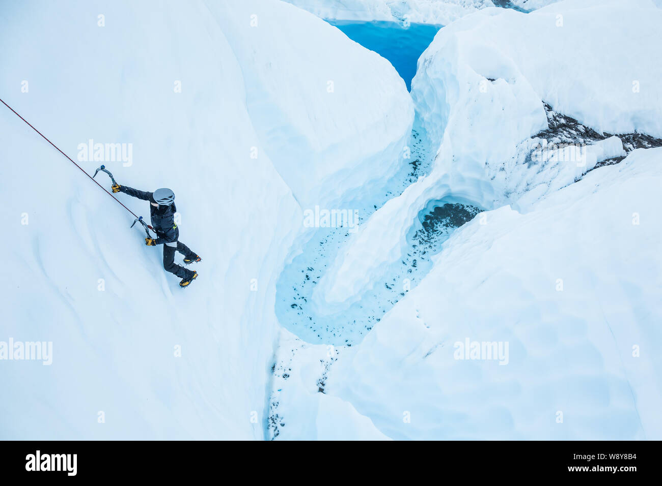 Seilschaft klettern vertikale Eis über einem Tiefblauen Pool auf der Matanuska Gletscher in Alaska. Stockfoto