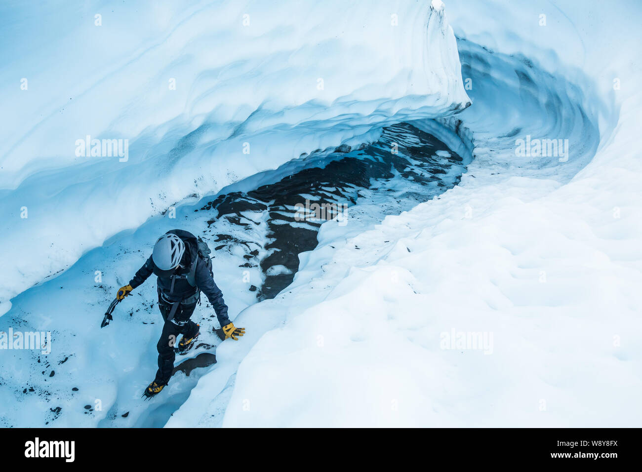 Junge Frau auf einem Gletscher durch einen schmalen Canyon von Eis auf dem Matanuska Gletscher in Alaska reisen. Stockfoto