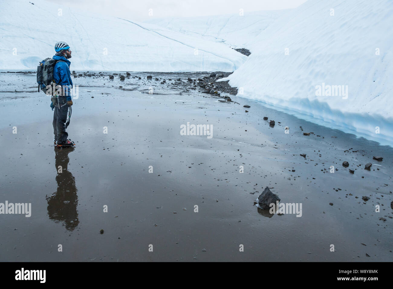 Mann im Regen stehen starrte auf einer großen Wand, die er in der Kälte des entfernten Alaska auf der Matanuska Gletscher Klettern wird. Stockfoto